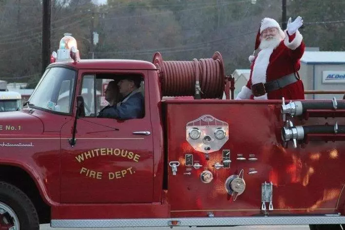 A Santa Claus Sanding on a Fire Truck